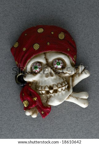 Scary pirate skull with cross bones and red head scarf on gray flec background.
