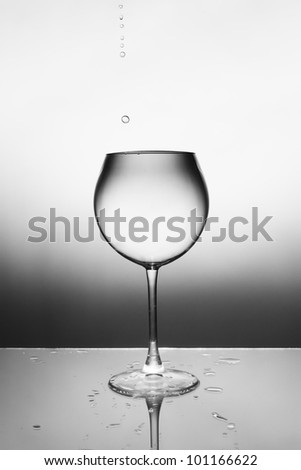 A glass of clear liquid and a drop falling into it. From the drop of fly spray.
