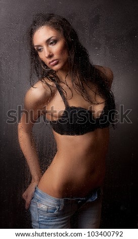Girl in a black bra and jeans for wet glass.
