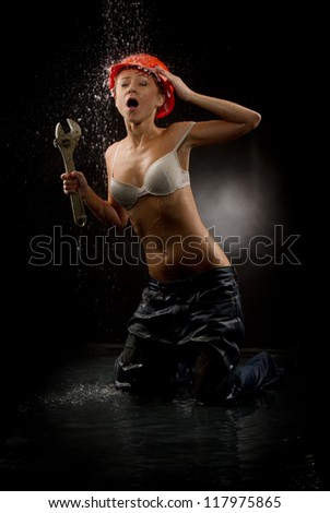 Wet in wet jeans with wrench in the helmet on a dark background.