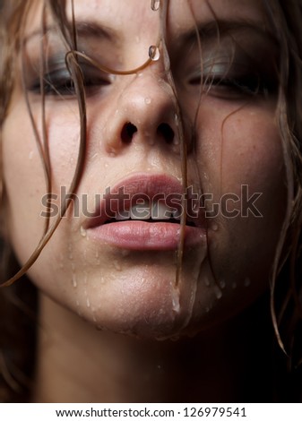 Portrait of a girl's face which water flows on a dark background.