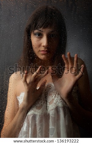The brunette in a white dress for a wet glass on a black background.