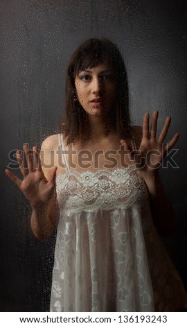 The brunette in a white dress for a wet glass on a black background.
