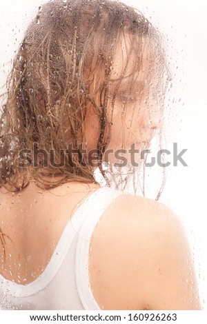 Portrait of a girl with wet hair, with a wet glass on a white background.