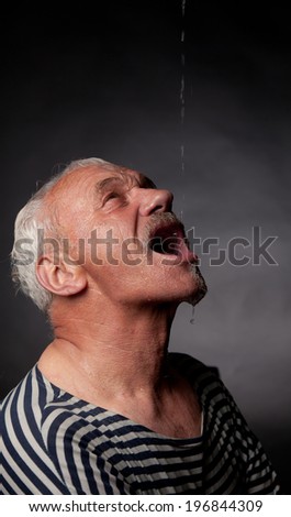 Portrait of a wet man on whom pours water on a dark background.