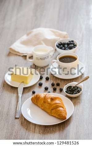 Breakfast with croissant,  milk, butter, huckleberry jam and coffee