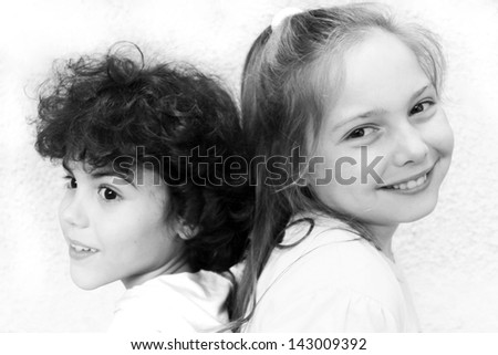Portrait of two kids back to back in black and white