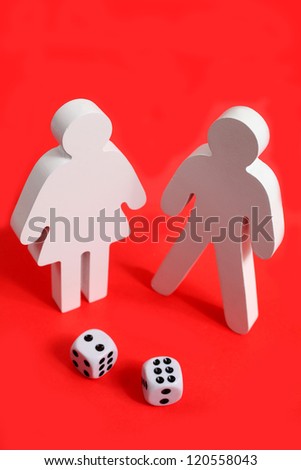 Wooden male and female figures on a red background with two dices in front of them