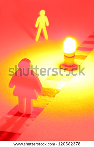 Warning light on chevron and two wooden figures standing in the glow