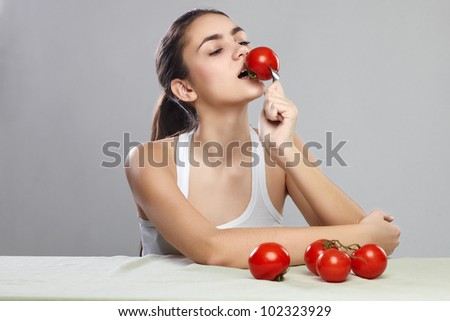 Woman bites tomato on a fork