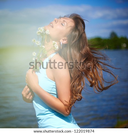 fashion portrait of beautiful sexy female brunette girl model lying on the river near the  in blue dress with a flower in his hand and with tears in his eyes