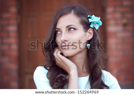 young beautiful brunette girl in a turquoise dress with a flower in her hair