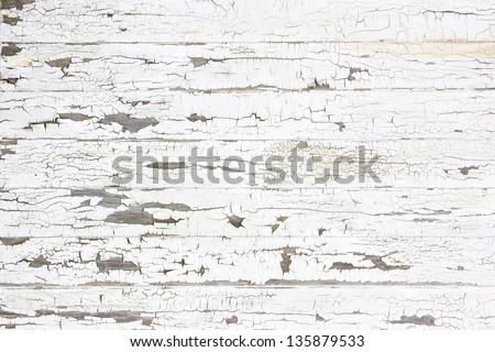 Wooden wall with white paint is severely weathered and peeling