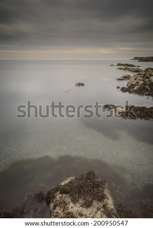 Dark clouds gather over the Irish Sea in this view from a secluded bay on the west coast of Anglesey in North Wales. Calm water and an incoming tide reveal the superb clarity of these coastal waters.