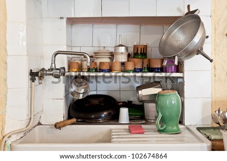 Sink of an old italian kitchen with pan, saucers and cups
