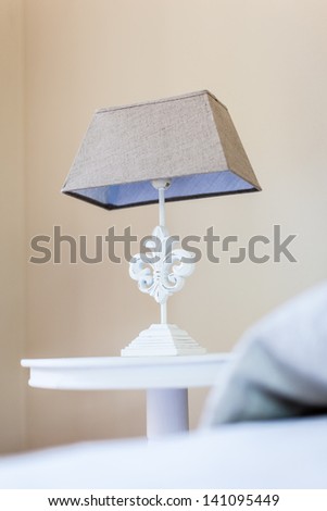a bed side table with a classical style bed lamp on it