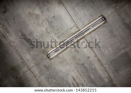 a fluorescent tube hanged on a concrete grungy ceiling