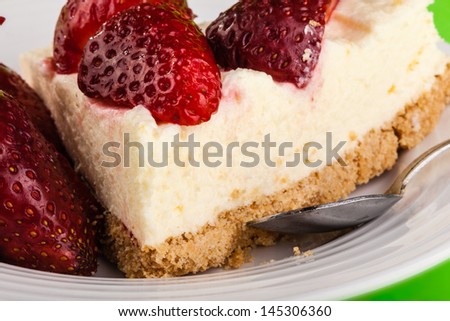 a delicious strawberry cheesecake in a white plate on a green background