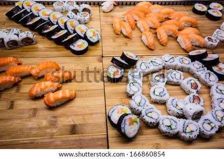 a lot of sushi rolls arranged on a wooden surface in a restaurant