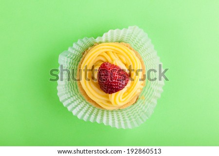 macro shot of a strawberry with custard over a green background