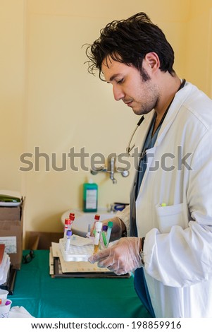 a young and handsome doctor holding a tray with blood samples