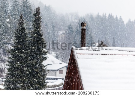 detail of a roof covered with snow with a smoking chimney