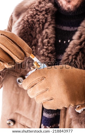 a young man wearing a sheepskin coat isolated over a white background holding a cigarette pack