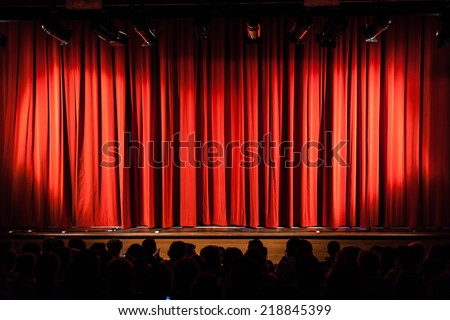 a closed red stage curtain in a small theater