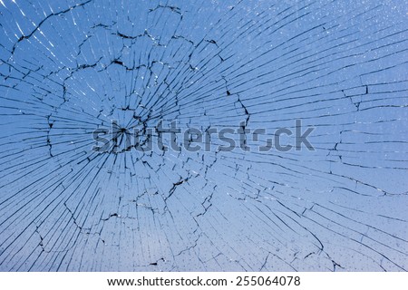 macro shot of a broken glass window against the blue sky