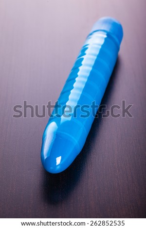 a blue ridged rubber dildo vibrator over a wooden surface