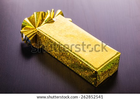 a golden wrapped gift box on a dark wooden surface
