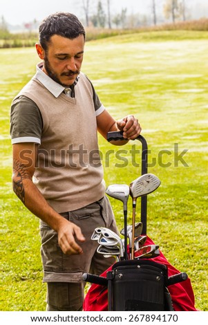a golf player playing on a beautiful golf course and a golf bag full of golf clubs
