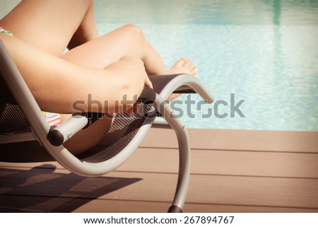closeup shot of a girl sunbathing on a chaise lounge at the pool side