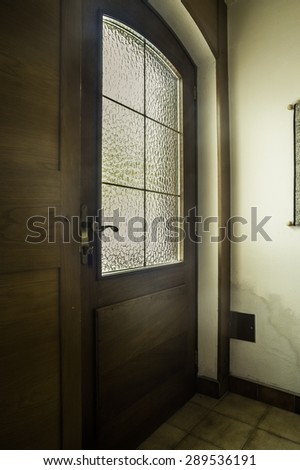 a gloomy wooden and glass door seen from inside a dark house