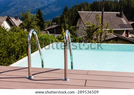 Grab bars ladder in blue swimming pool in a garden in Austria