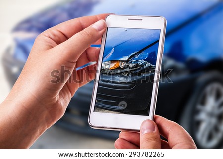 a woman using a smart phone to take a photo of the damage to her car caused by a car crash