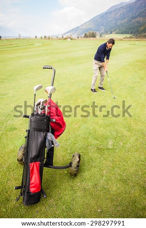 a golf player playing on a beautiful golf course and a golf bag full of golf clubs