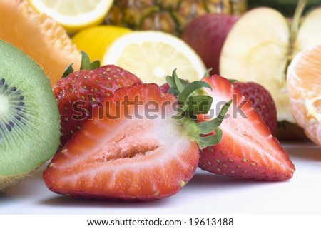 Cut strawberries on a background of a heap of cut fruits