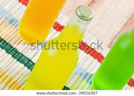 Ice cold tropical drinks in wet bottles on wooden table