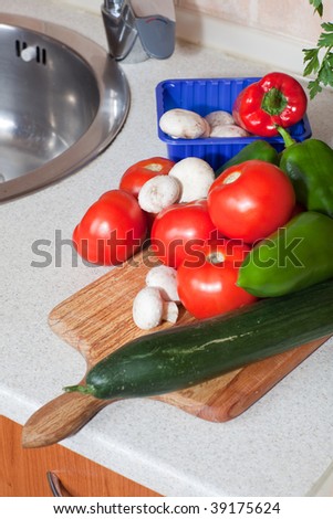 Heap of fresh veggies on wooden board next to the kitchen sink