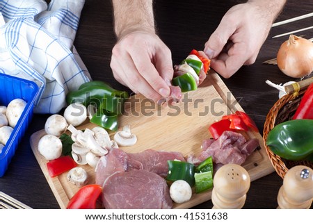 A person making meat sticks with pork meat and fresh veggies