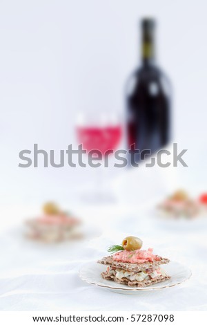 Small sandwich on white table top with bottle of wine on the background