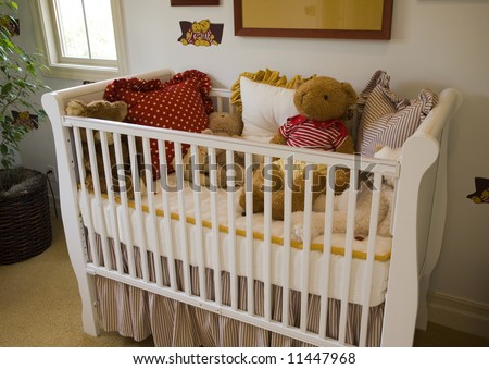 Baby bedroom with crib, pillows and a teddy bear.