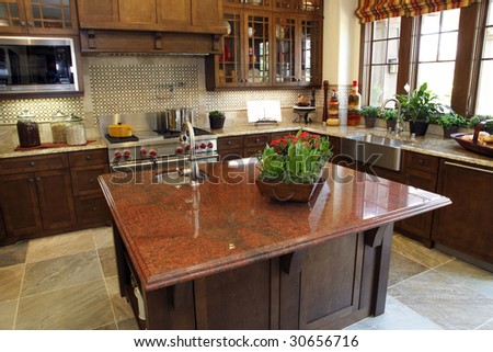 Modern designer kitchen with brown tiles and a granite island.