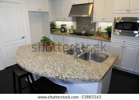 Modern designer kitchen with stainless steel appliances and a granite island.