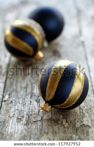 three blue christmas ornaments made of blue and gold glass on a wooden plank.