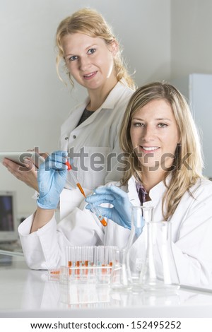 Scientists at the laboratory with chemicals and tablet computer