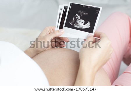 Close up of pregnant woman holding ultrasound scan and mother pass