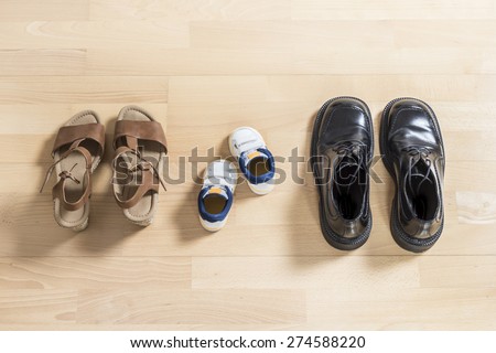 Three pair of shoes in father big, mother medium and son or daughter small kid size representing family, growth, education and togetherness concept
