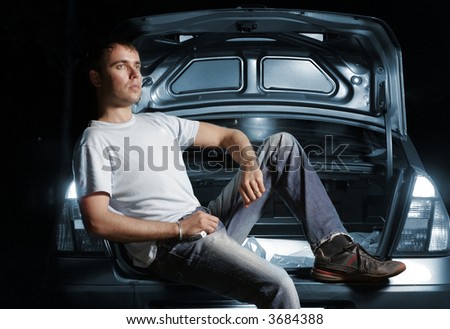 young man sitting in the opened car boot